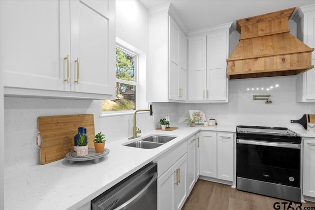 kitchen with custom exhaust hood, stainless steel appliances, sink, light hardwood / wood-style flooring, and white cabinets