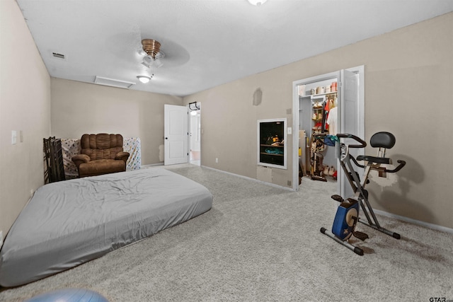 carpeted bedroom with a walk in closet, ceiling fan, and a closet