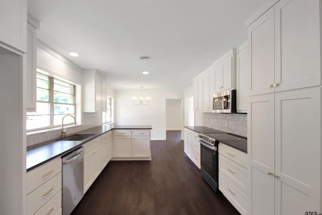 1301 Roseland Blvd, Tyler, TX 75701 - kitchen featuring appliances with stainless steel finishes, a peninsula, a chandelier, recessed lighting, and white cabinets