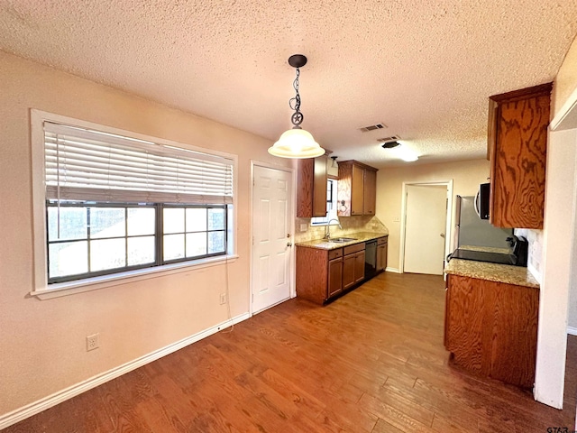 kitchen featuring decorative light fixtures, a textured ceiling, dark hardwood / wood-style flooring, sink, and dishwasher