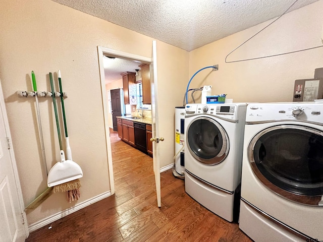 washroom with a textured ceiling, hardwood / wood-style flooring, sink, and washer and dryer