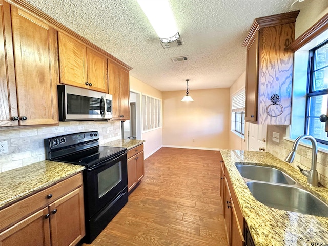 kitchen with a wealth of natural light, black range with electric stovetop, sink, and light hardwood / wood-style floors