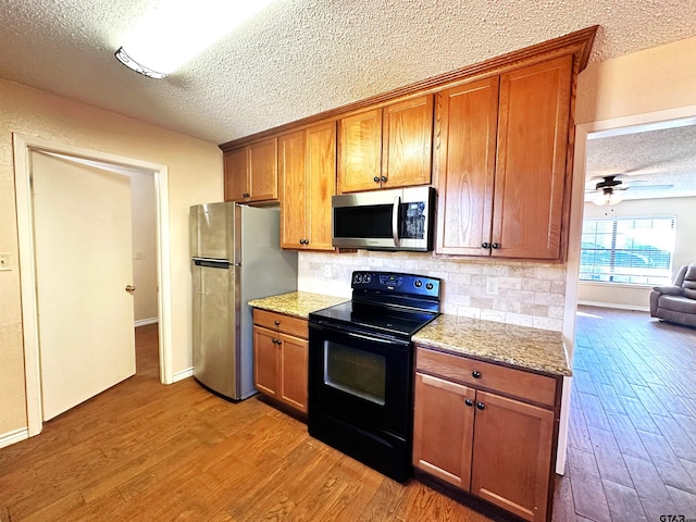 kitchen with stainless steel appliances, light hardwood / wood-style floors, ceiling fan, and a textured ceiling