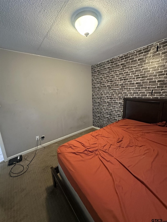 unfurnished bedroom with carpet floors, brick wall, a textured ceiling, and baseboards