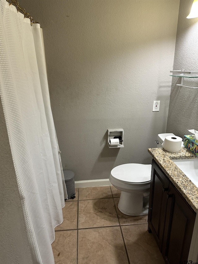 full bath featuring a textured wall, toilet, vanity, baseboards, and tile patterned floors