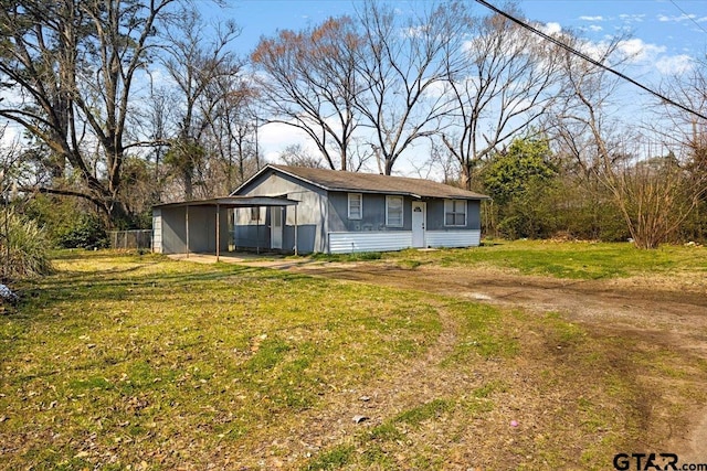 ranch-style home with a front lawn and dirt driveway