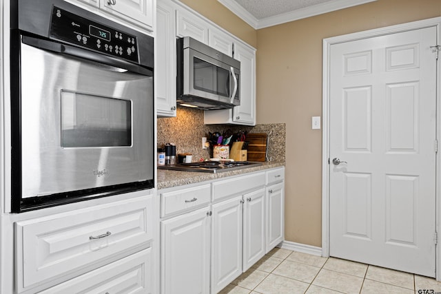 2207 Pinecrest Dr, Gladewater, TX 75647 - kitchen with appliances with stainless steel finishes, light tile patterned flooring, ornamental molding, and white cabinets