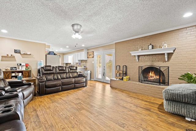 2207 Pinecrest Dr, Gladewater, TX 75647 - living area featuring french doors, a textured ceiling, a brick fireplace, ceiling fan, and light wood finished floors