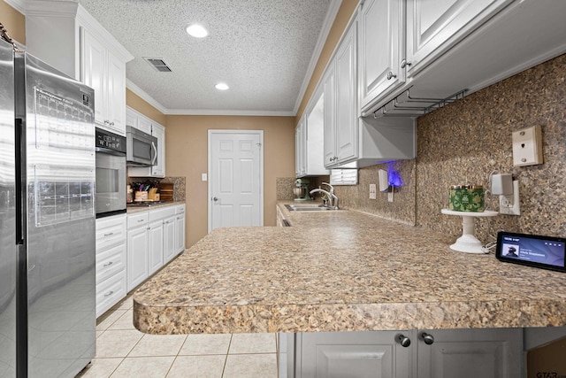 2207 Pinecrest Dr, Gladewater, TX 75647 - kitchen with a textured ceiling, white cabinetry, visible vents, a sink, and stainless steel appliances