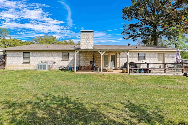 2207 Pinecrest Dr, Gladewater, TX 75647 - rear view of house featuring a lawn, fence, brick siding, a chimney, and central AC unit