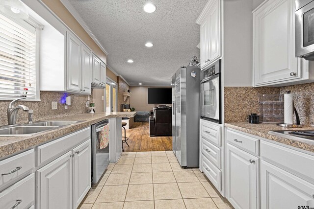 2207 Pinecrest Dr, Gladewater, TX 75647 - kitchen featuring open floor plan, white cabinetry, light tile patterned flooring, appliances with stainless steel finishes, and a sink