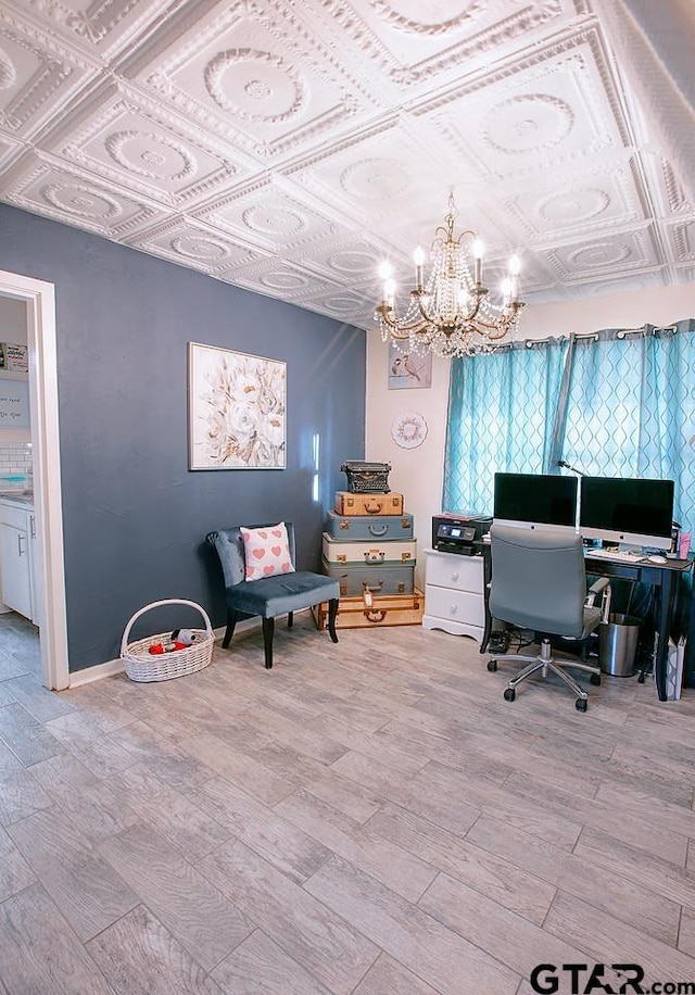 home office with light wood-type flooring and a chandelier