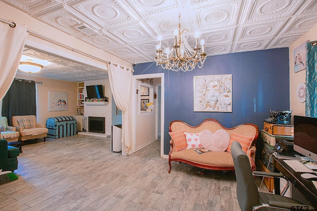 living area with a large fireplace, hardwood / wood-style floors, and an inviting chandelier