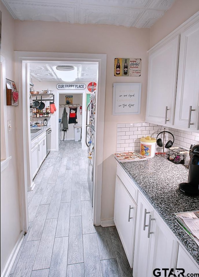 kitchen with tasteful backsplash, white cabinetry, and light wood-type flooring