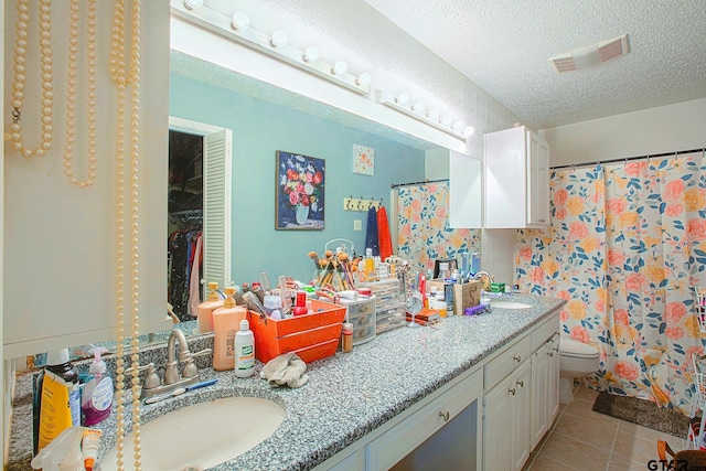 bathroom featuring vanity, tile patterned floors, toilet, a textured ceiling, and walk in shower