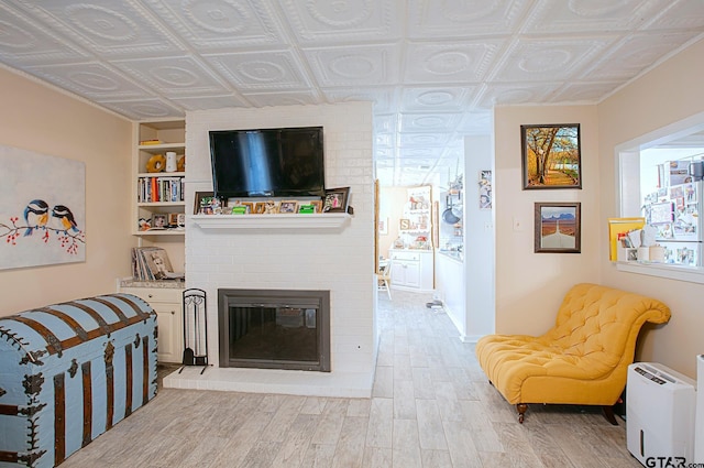 living room featuring a fireplace, plenty of natural light, built in features, and light wood-type flooring