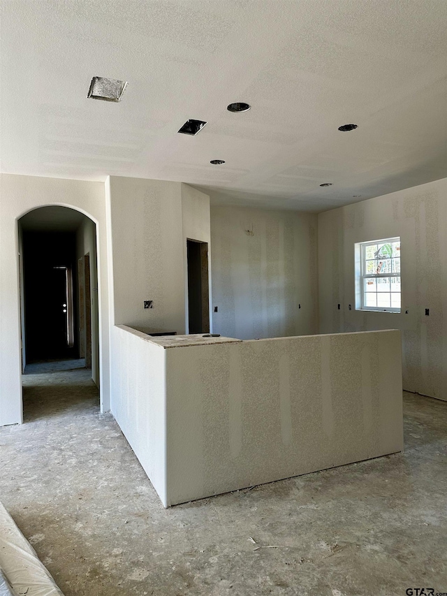 empty room with arched walkways and a textured ceiling