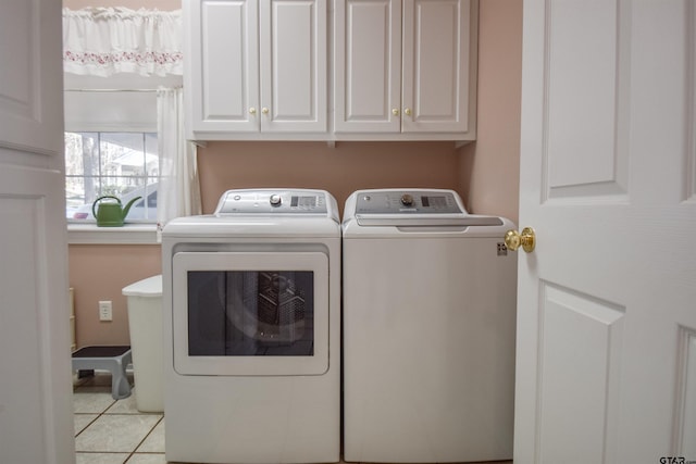 laundry room with cabinets, light tile patterned floors, and washer and dryer