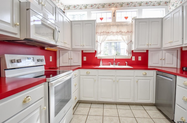 kitchen featuring white cabinetry, sink, light tile patterned flooring, and white appliances