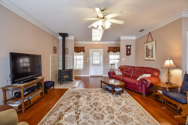 living room featuring crown molding, ceiling fan, hardwood / wood-style floors, and a wood stove