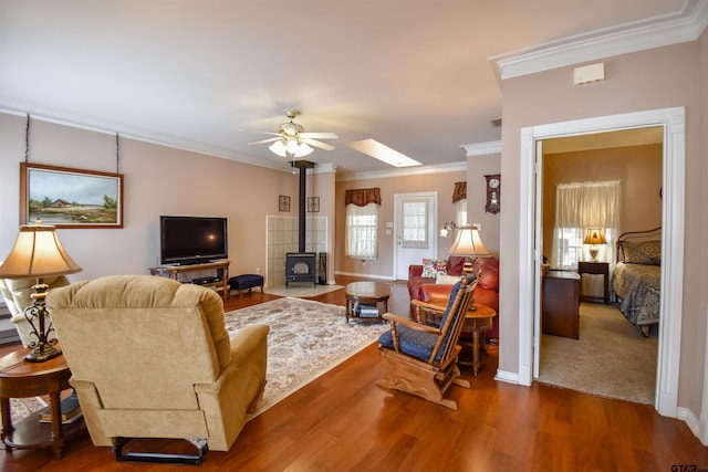 living room featuring crown molding, dark wood-type flooring, ceiling fan, and a wood stove