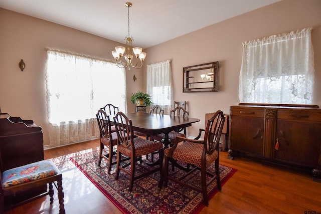 dining area with dark wood-type flooring and an inviting chandelier