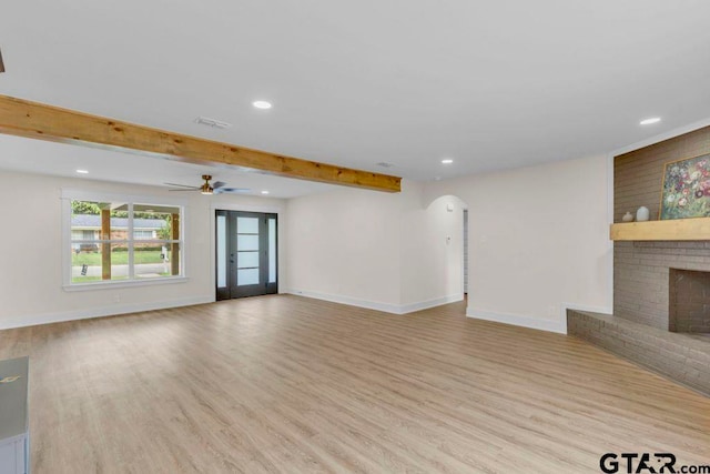 8100 Jewell Ln, Tyler, TX 75703 - unfurnished living room featuring wood finished floors, arched walkways, a fireplace, baseboards, and recessed lighting