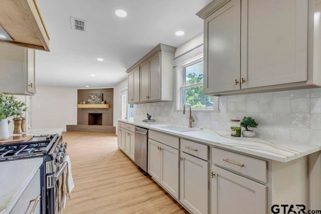 8100 Jewell Ln, Tyler, TX 75703 - kitchen with a sink, stainless steel appliances, open floor plan, backsplash, and light wood-style floors