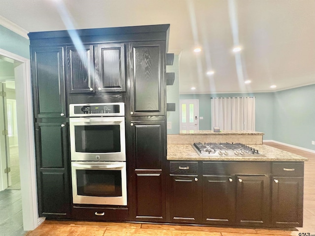 kitchen with light wood-type flooring, stainless steel appliances, crown molding, and light stone countertops