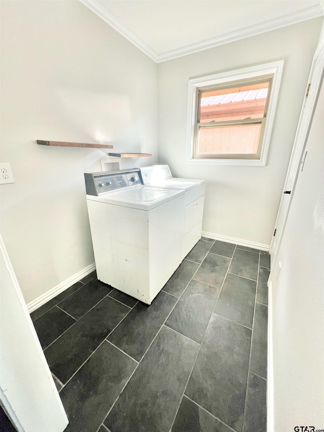 clothes washing area with ornamental molding, washing machine and dryer, and dark tile patterned flooring