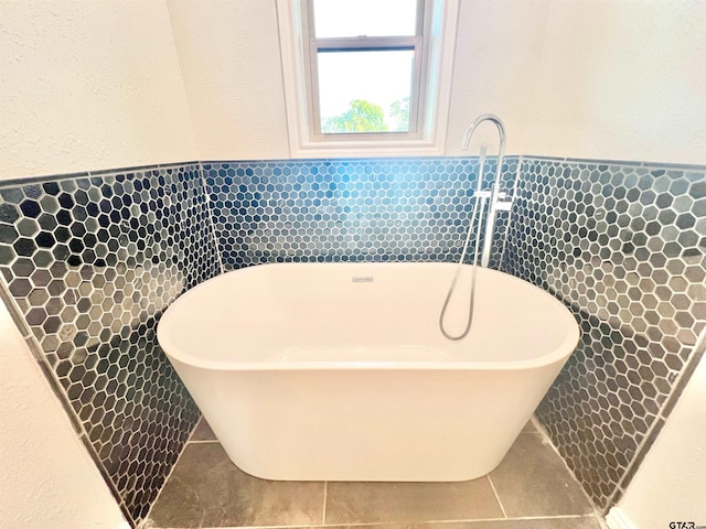 bathroom featuring a tub to relax in, tile patterned flooring, and tile walls