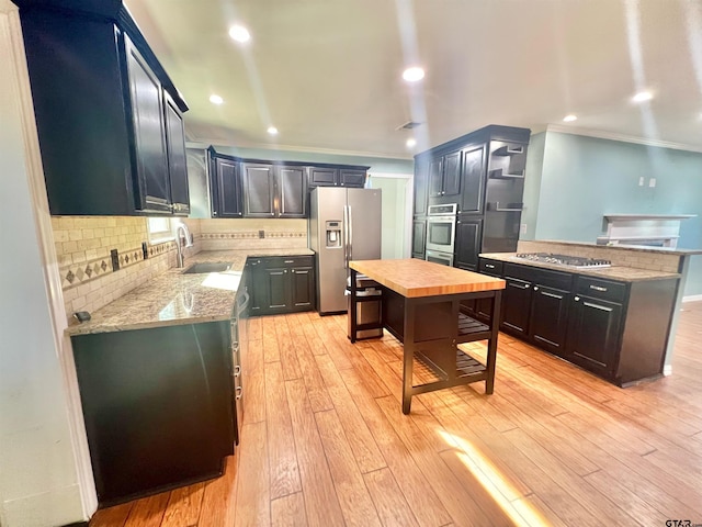 kitchen with crown molding, appliances with stainless steel finishes, light stone countertops, decorative backsplash, and light hardwood / wood-style floors