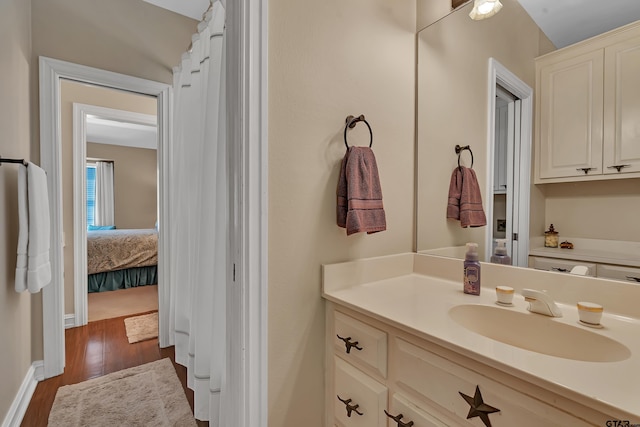 1014 Lovers Ln, Longview, TX 75604 - bathroom featuring wood finished floors, vanity, connected bathroom, and baseboards