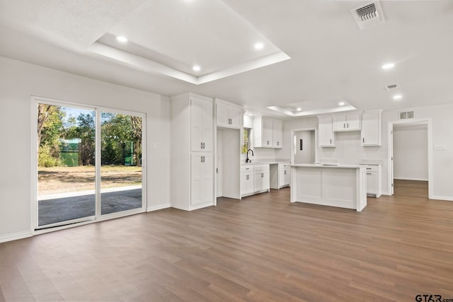 kitchen with a tray ceiling, white cabinets, and a kitchen island