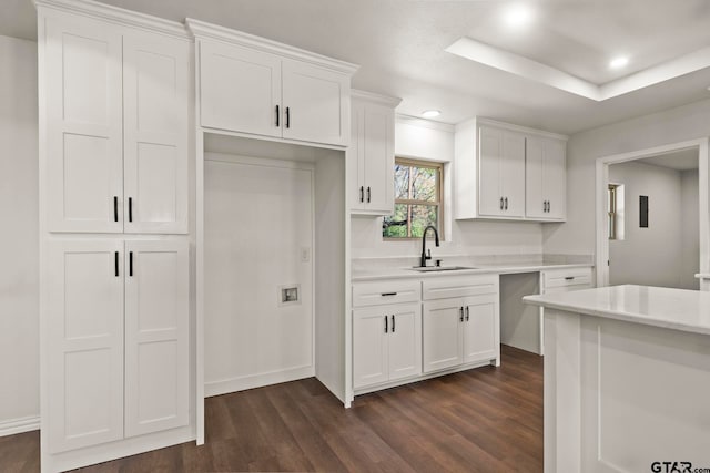 kitchen featuring a raised ceiling, sink, white cabinetry, and dark wood-type flooring