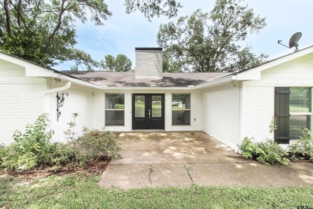 17893 Slack Rd, Whitehouse, TX 75791 - view of exterior entry featuring french doors, a chimney, brick siding, a shingled roof, and a patio area