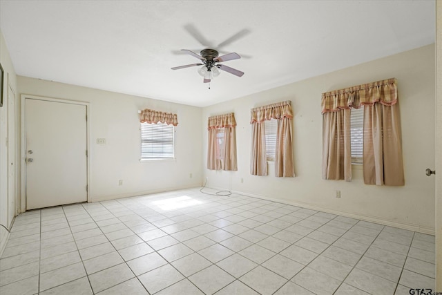 spare room featuring baseboards, a ceiling fan, and light tile patterned floors