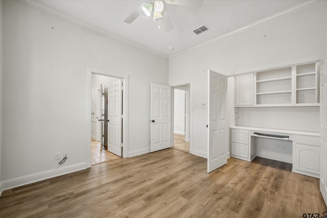 unfurnished bedroom featuring built in study area, visible vents, light wood finished floors, and ornamental molding