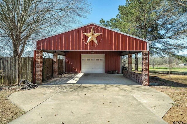 garage with a detached garage, driveway, and fence