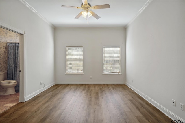 empty room featuring wood finished floors, ornamental molding, baseboards, and ceiling fan