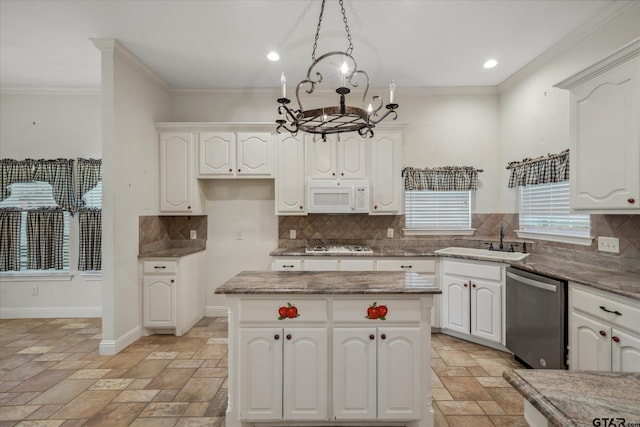 kitchen with stone tile flooring, a sink, an inviting chandelier, white microwave, and dishwasher