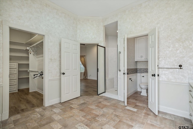 unfurnished bedroom with wallpapered walls, a closet, a spacious closet, ornamental molding, and stone finish floor