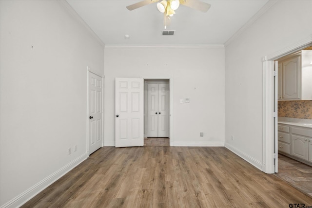 unfurnished bedroom featuring baseboards, crown molding, visible vents, and light wood-style flooring