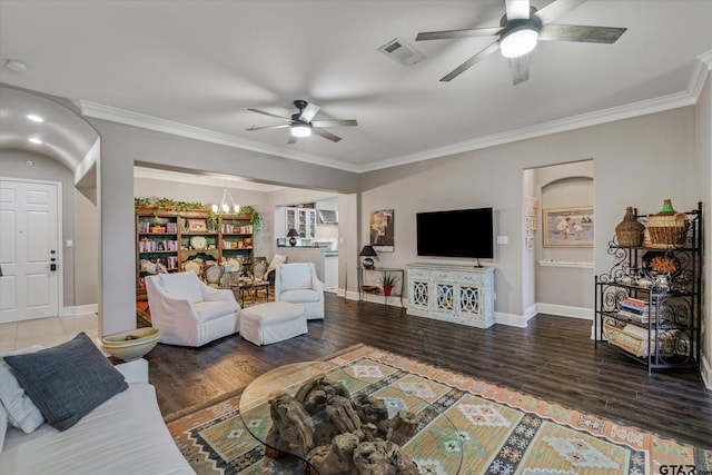 living room with ceiling fan with notable chandelier, crown molding, and dark wood-type flooring