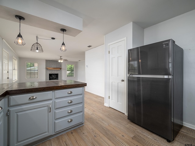 kitchen with dark countertops, a fireplace, freestanding refrigerator, open floor plan, and light wood-style flooring