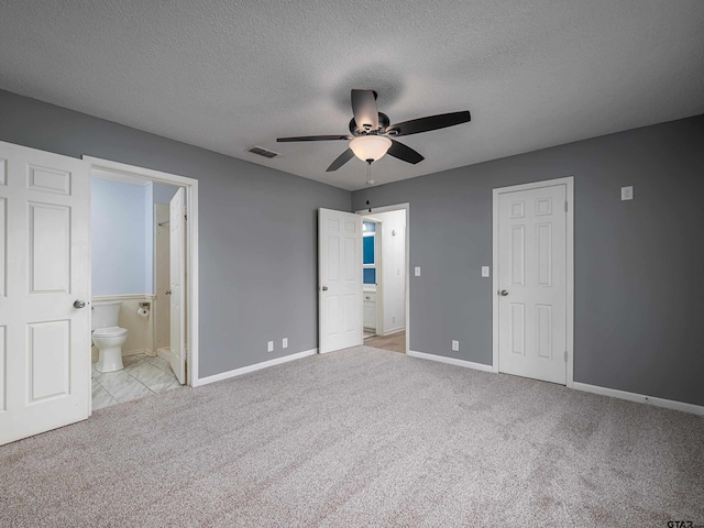 unfurnished bedroom featuring carpet floors, a textured ceiling, baseboards, and visible vents