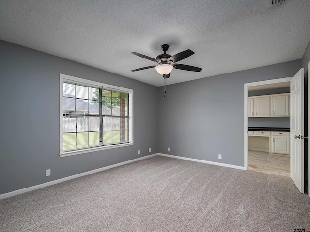 unfurnished bedroom featuring baseboards, ceiling fan, light carpet, and a textured ceiling