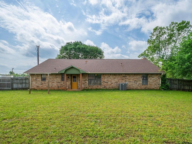 rear view of house with a lawn, a fenced backyard, brick siding, and cooling unit