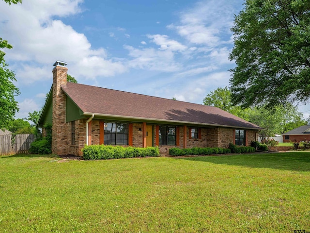 ranch-style house featuring brick siding, a front lawn, fence, and a chimney