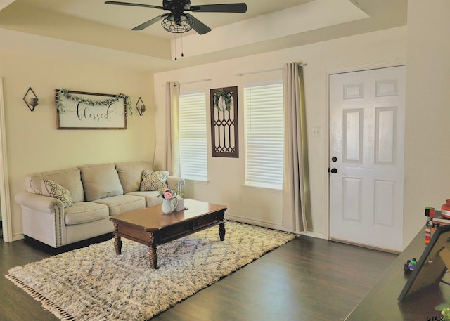 living room with dark hardwood / wood-style floors, ceiling fan, and a tray ceiling